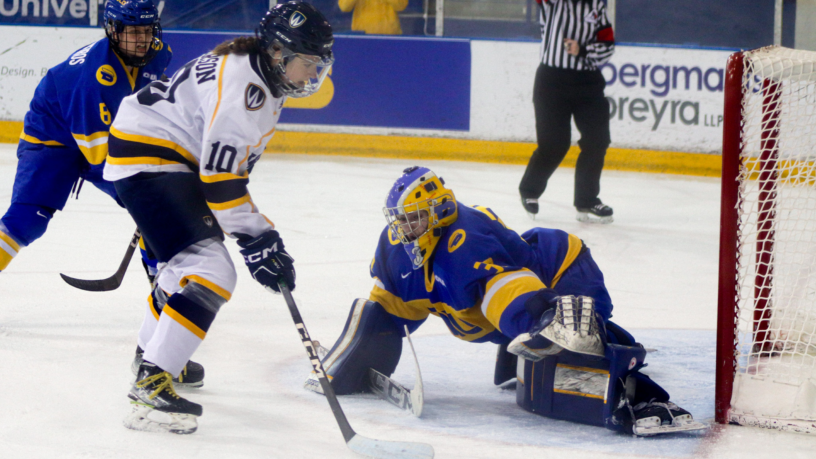 A member of the Windsor Lancers women's hockey team skates to the net with the puck as she faces the TMU Bold women's hockey goalie