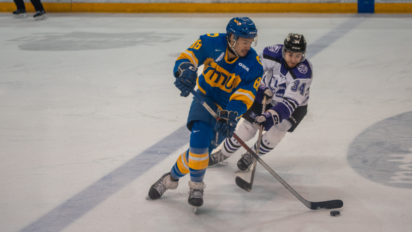 TMU Bold men's hockey player Kyle Bollers faces against a Western Mustangs player