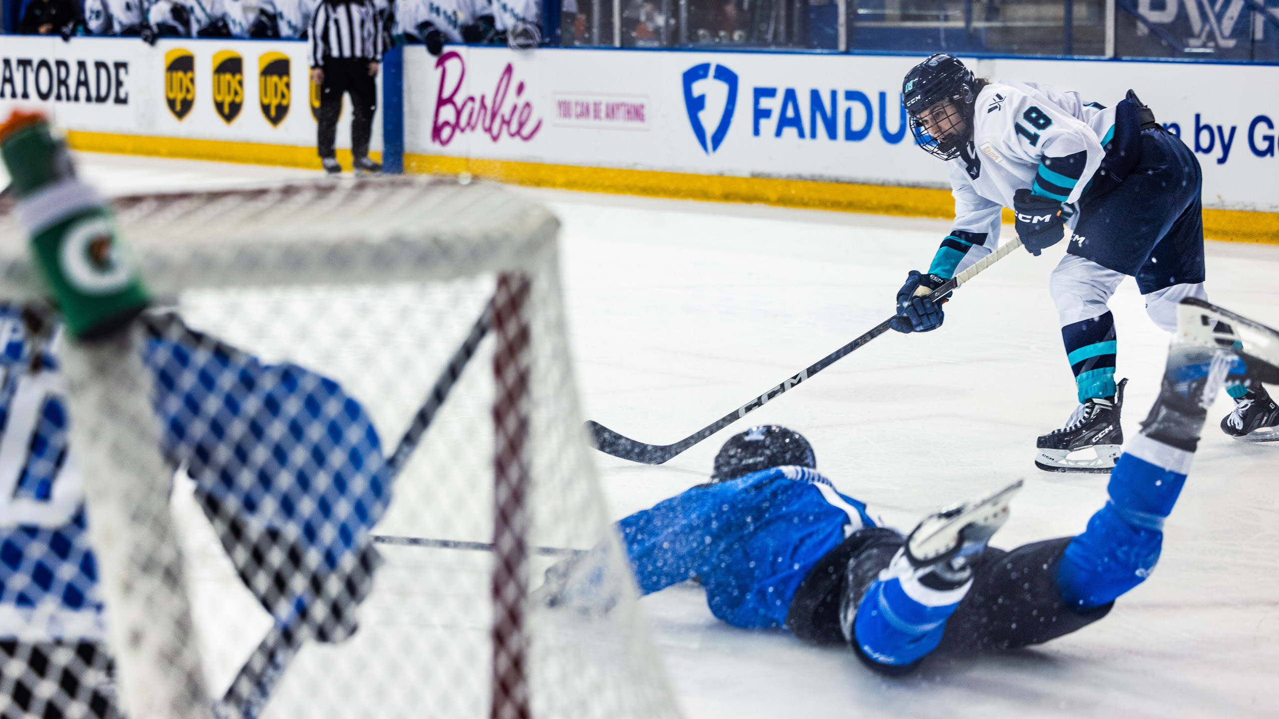 A PWHL New York player prepares to shoot the puck as a Toronto player slides across the ice to block it
