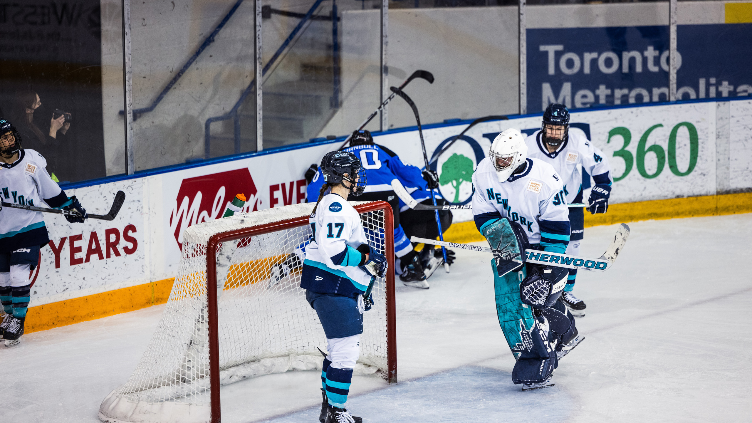 PWHL Toronto players celebrate a goal huddled on the ice
