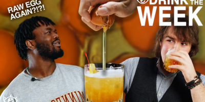 top right corner reads, "drink of the week" two people on either side looking surprised with an orange drink in the center