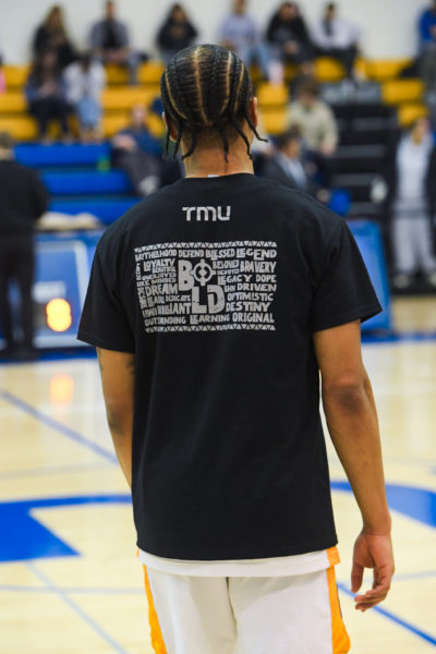 TMU men's basketball player Cameron Ramage stands on the court while wearing the Black History Month-designed shirt
