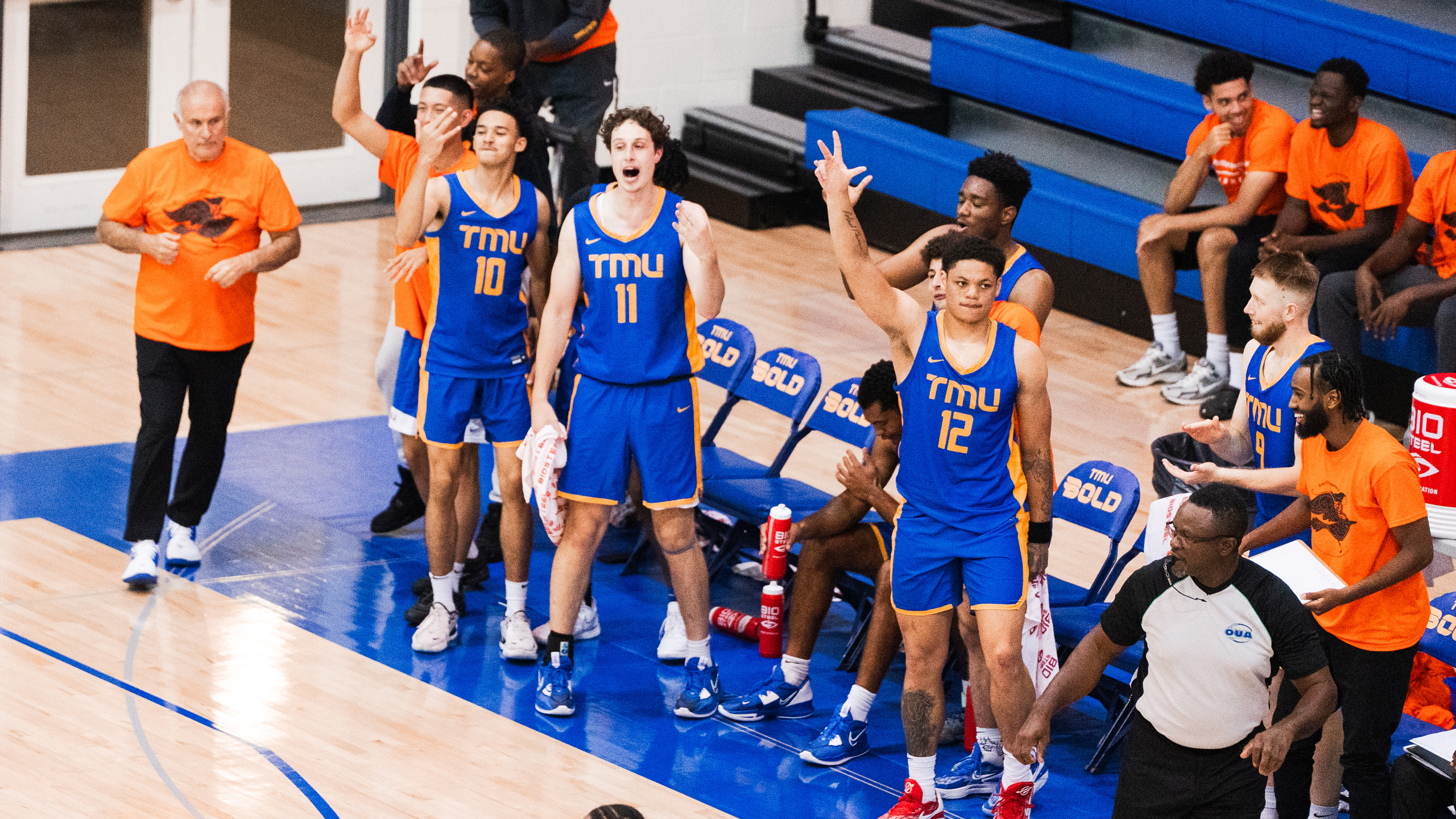 TMU men's basketball players celebrate on the bench