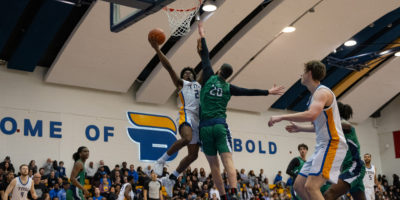 TMU men's basketball player Gabe Gutsmore goes up for a layup against a Nipissing defender