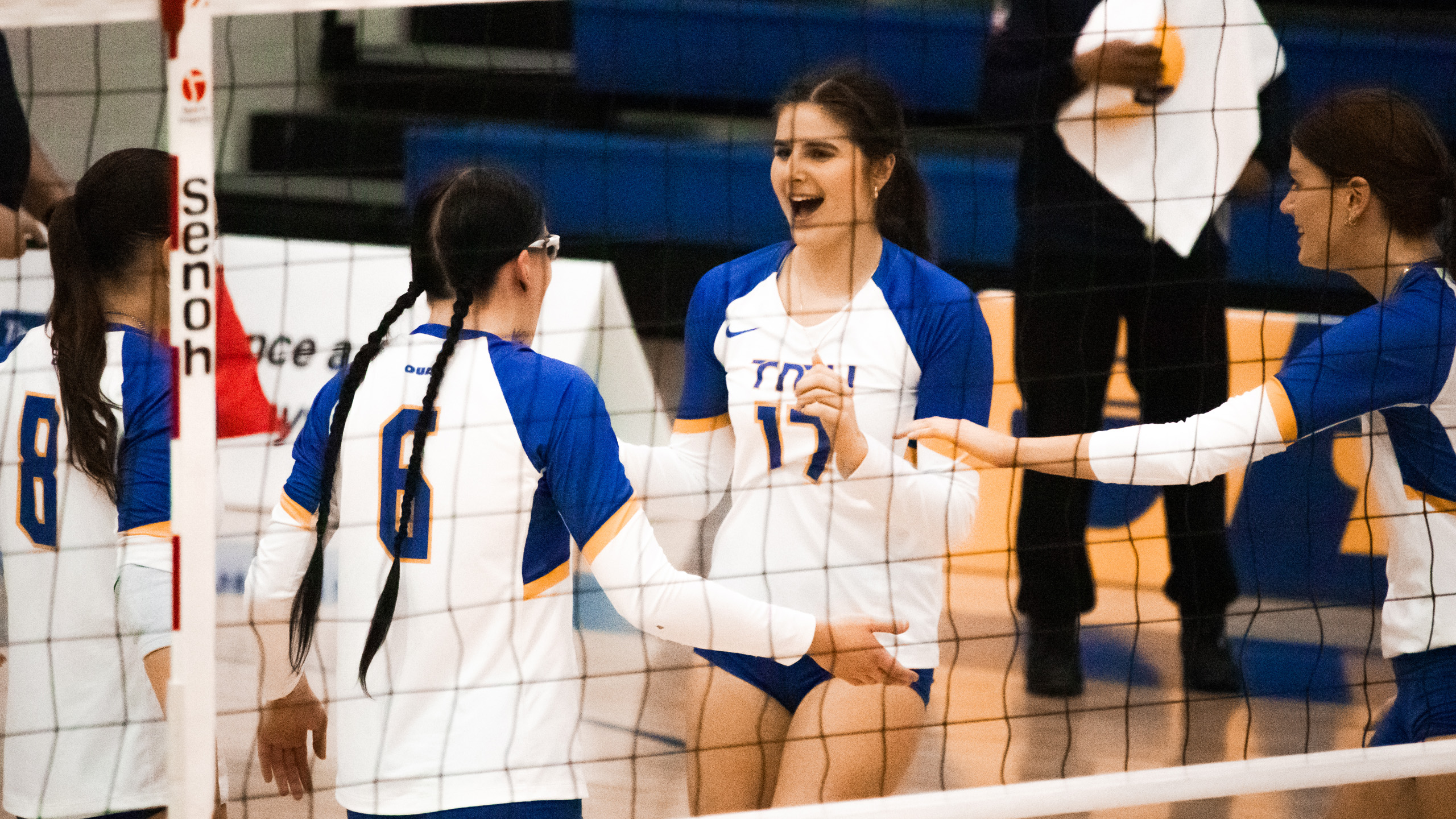 TMU women's volleyball screams in celebration of a point and high-fives her teammates