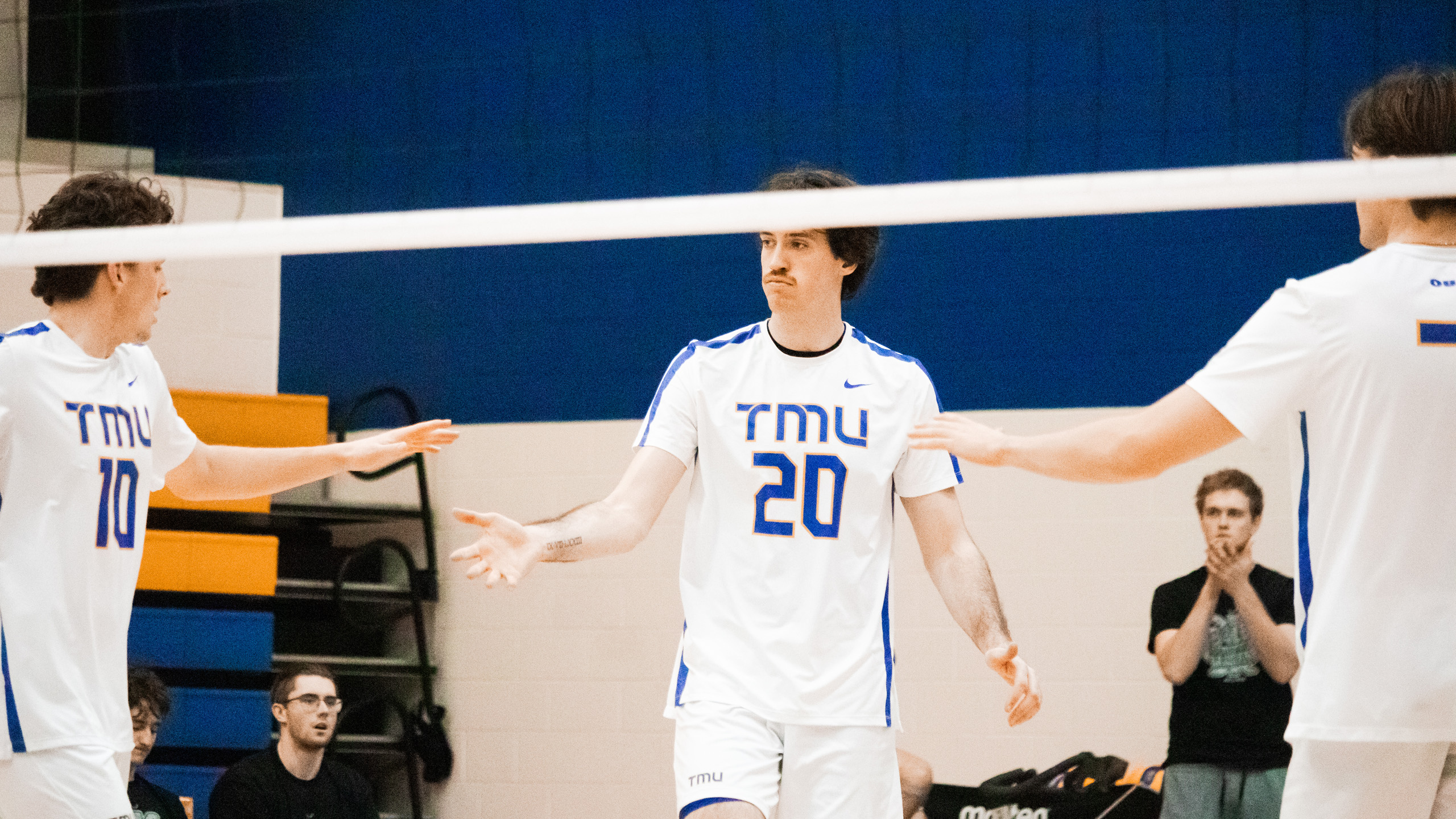 TMU men's volleyball player Alex King high fives his teammates on the court