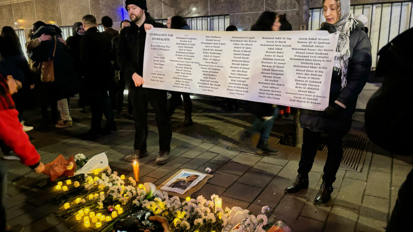 a poster with names is held up by two people at a vigil