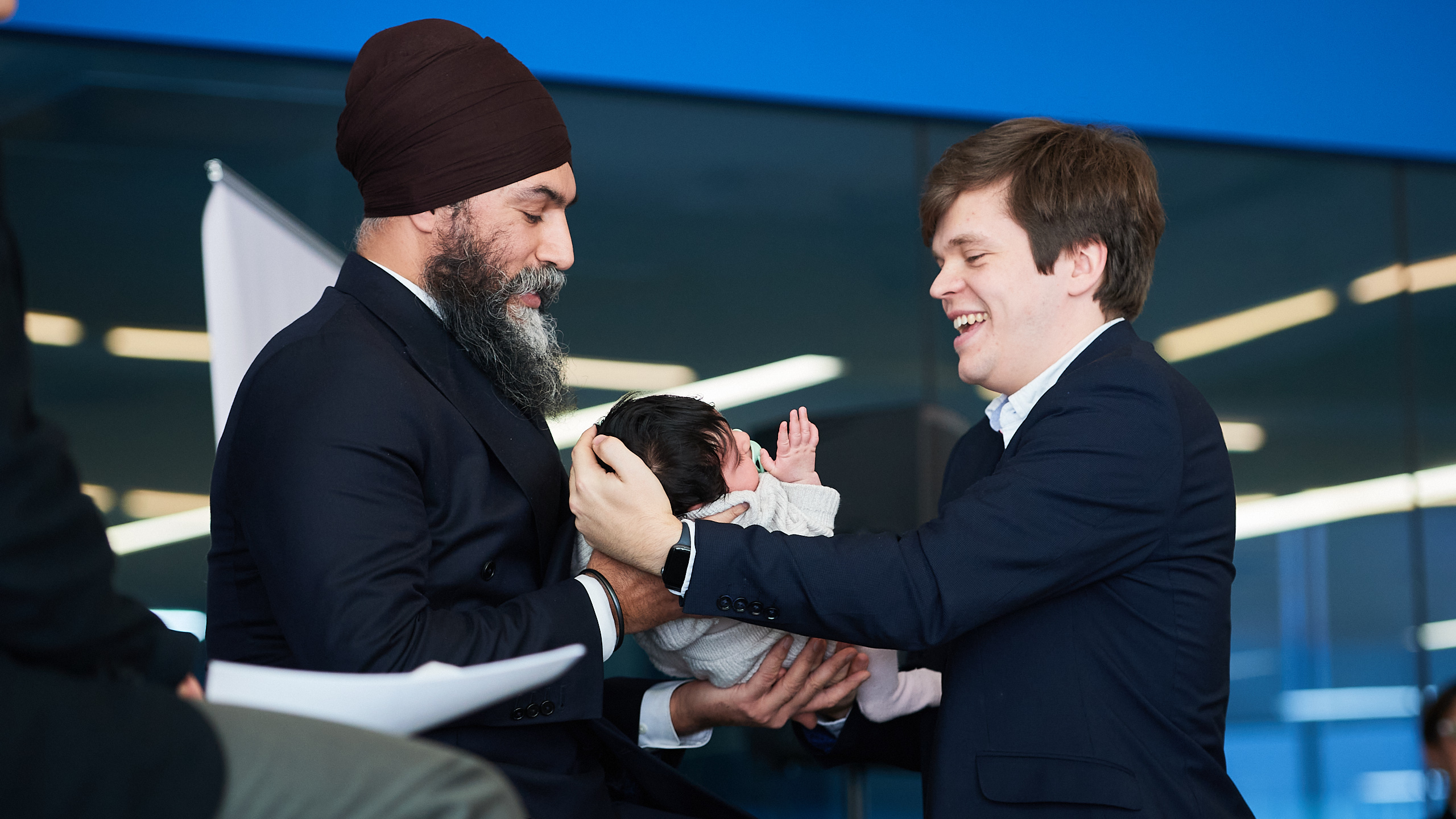 Jagmeet Singh holds his child on stage as a staffer helps him