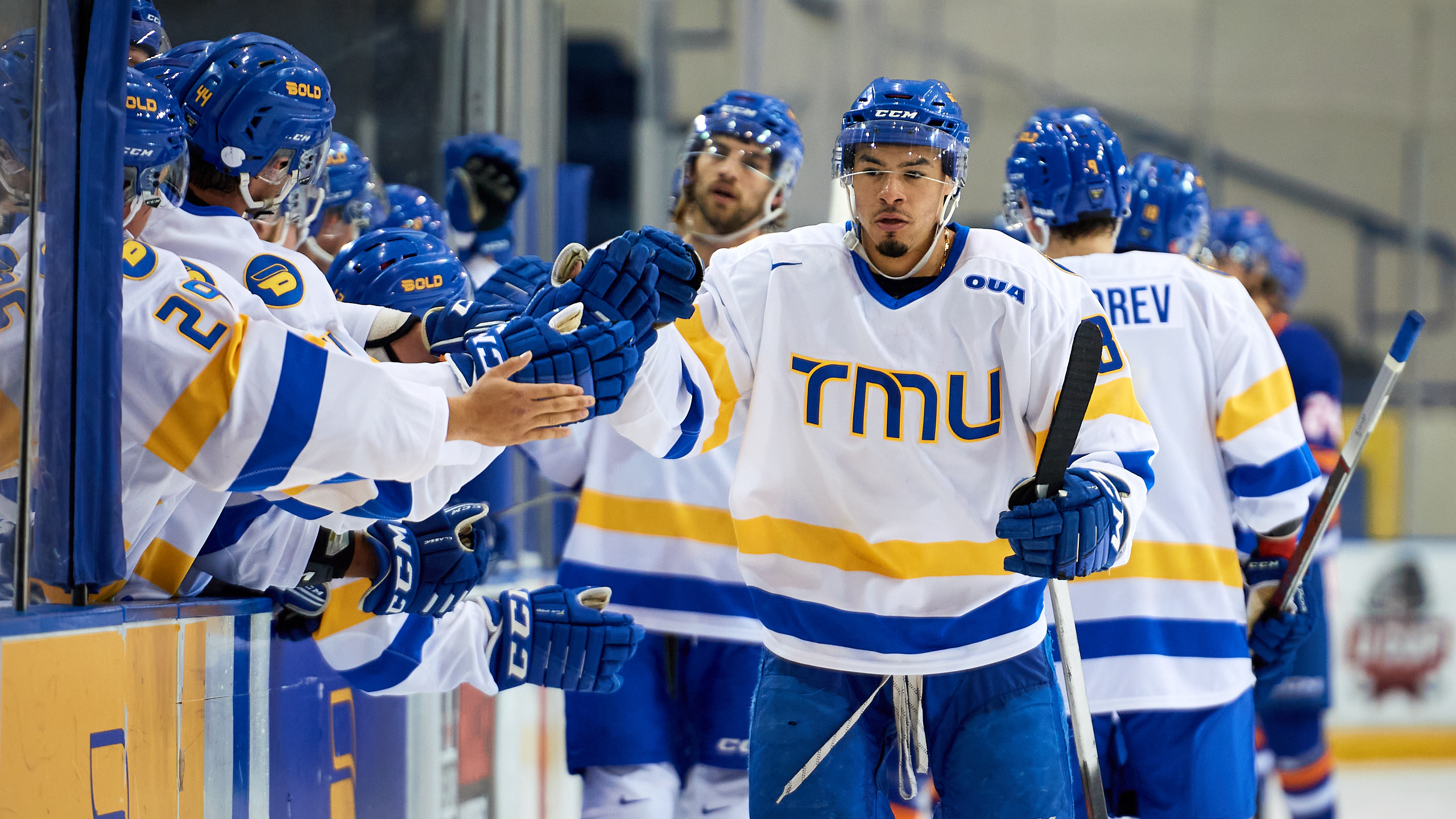 TMU men's hockey player Kyle Bollers fist bumps his teammates after he scores a goal