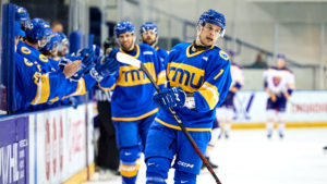 TMU men's ice hockey player Zach Roberts fist bumps his teammates after a goal