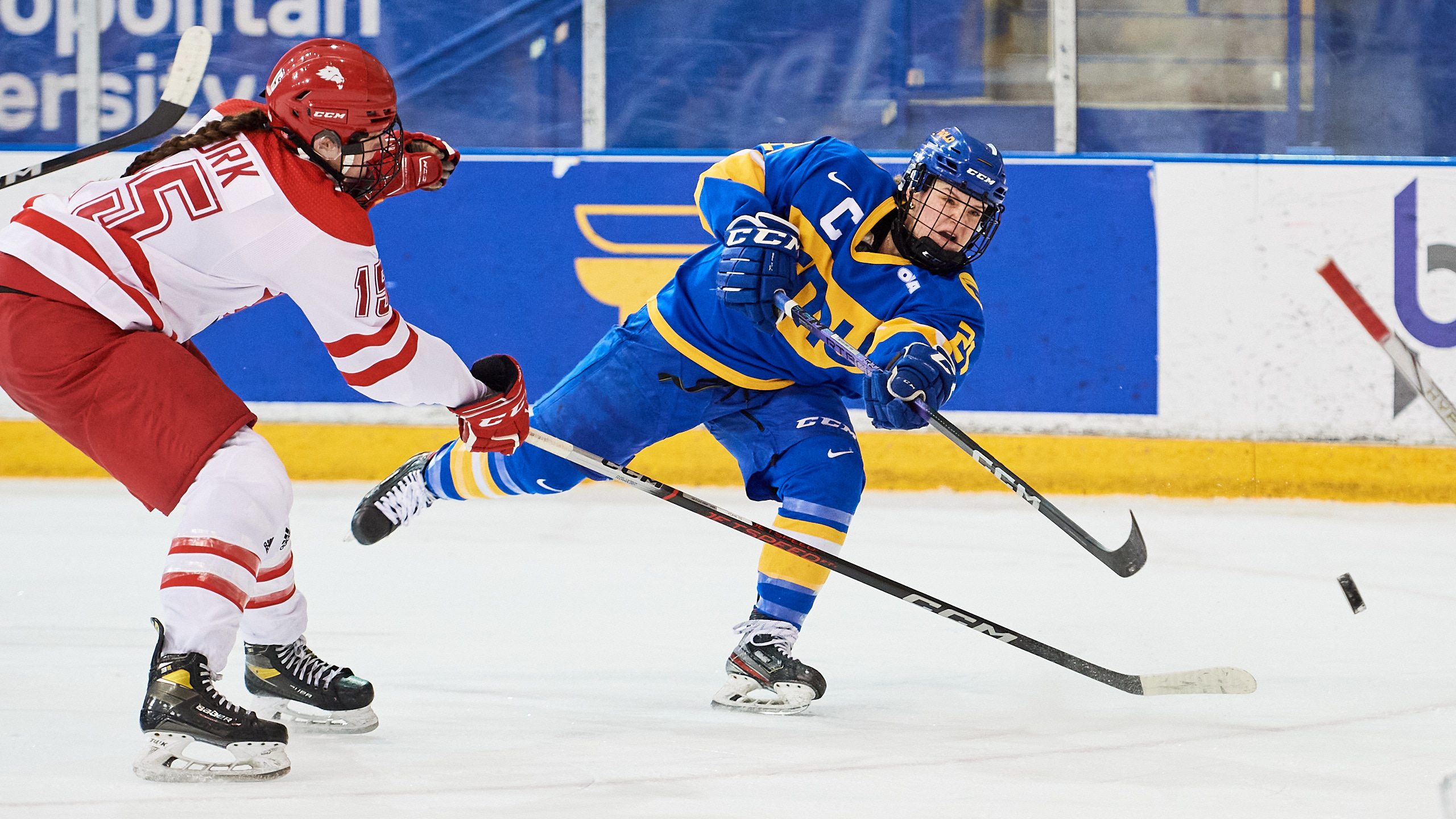 TMU women's hockey player Emily Baxter shoots a puck while being defended by a York defender