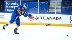 TMU men's ice hockey player Kyle Bollers shoots the puck into the empty net