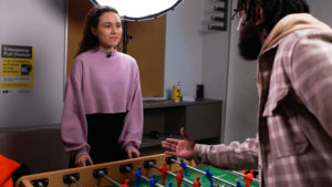 Ilyas leans over a foosball table to shake Daniella's hand