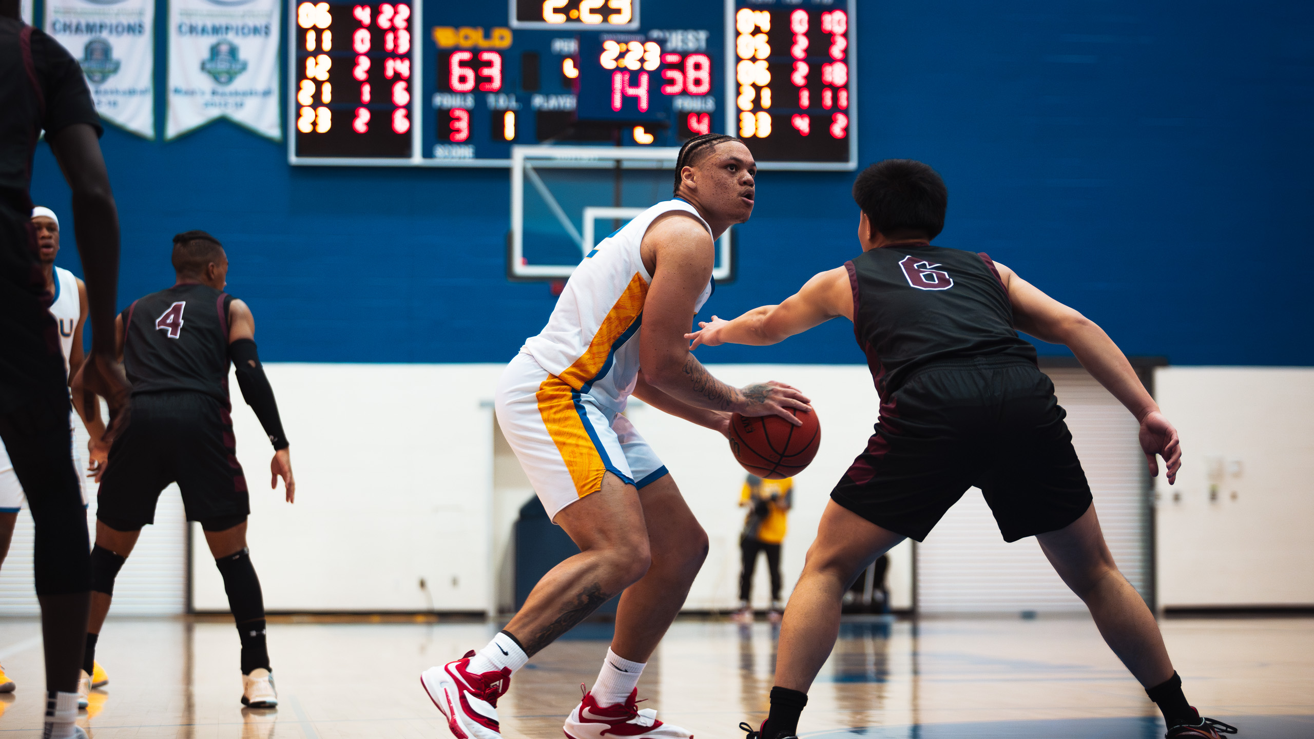 TMU men's basketball player Aaron Rhooms holds the ball above his knee as he is guarded by a McMaster Marauders defender