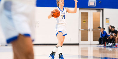 TMU Bold women's basketball player Kaillie Hall holds up two fingers as she dribbles a basketball up the court