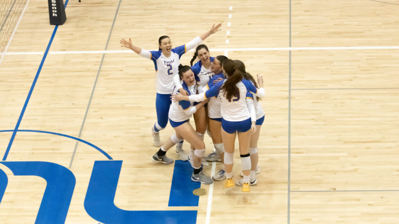 Members of the TMU Bold women's volleyball team celebrate on court after their win over the Western Mustangs