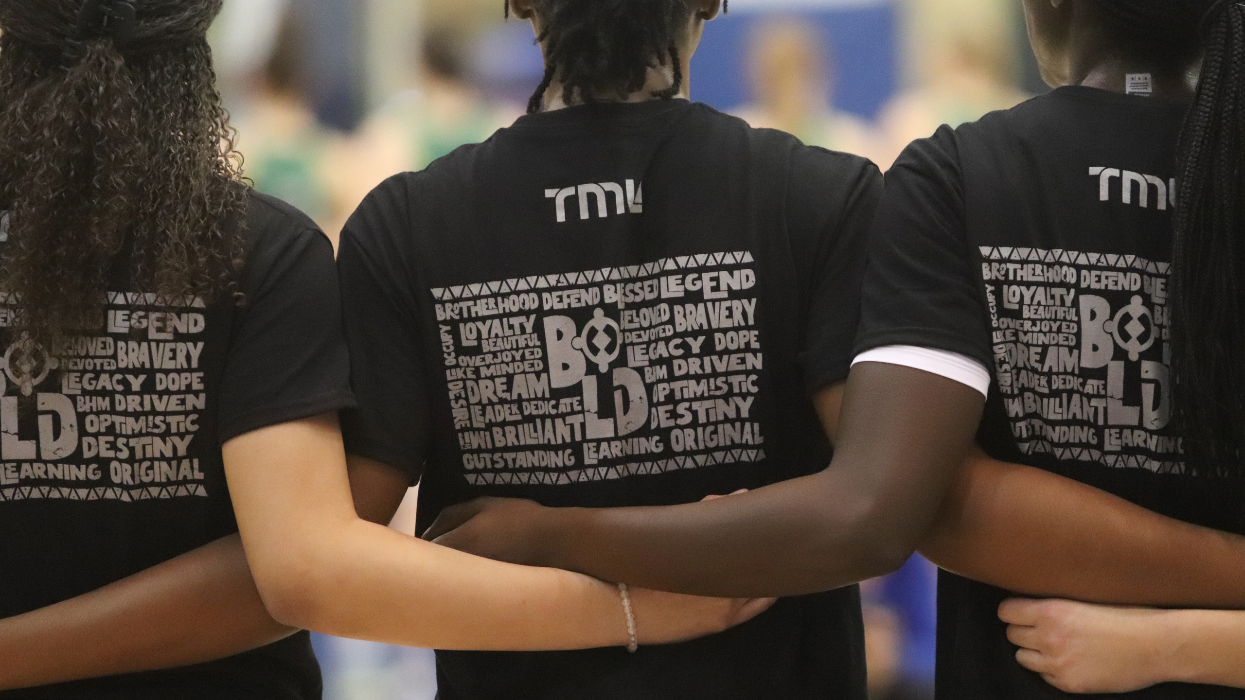 TMU Bold women's basketball team stands with their arms locked wearing a Black History Month shirt