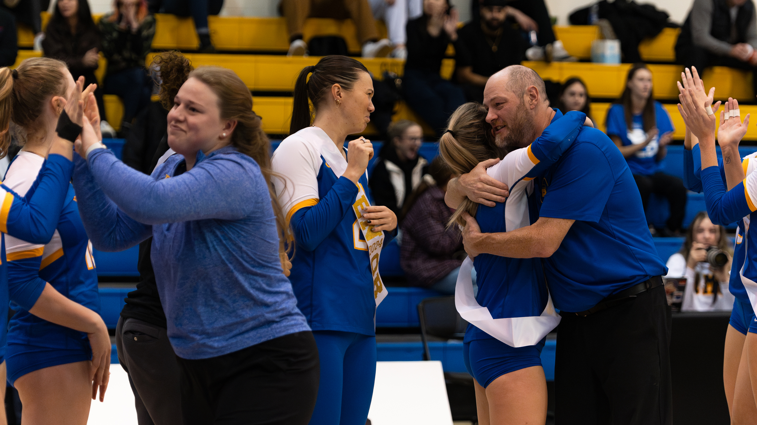 Seniors from the TMU Bold women's volleyball team hug coaches