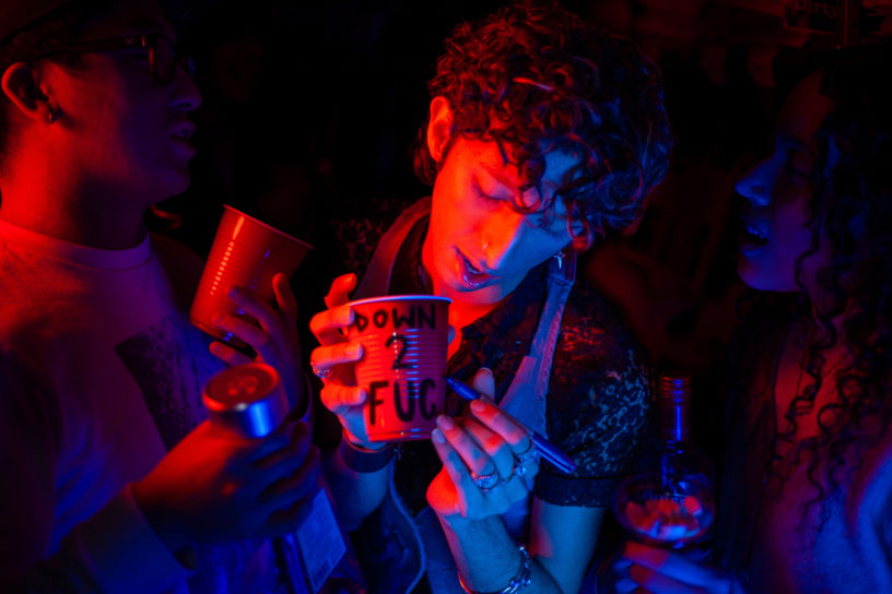 Three people holding drinks lit up with pink lights