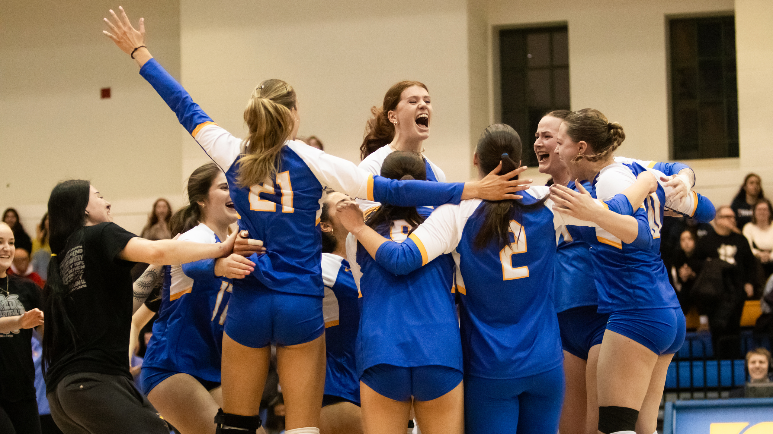 The TMU Bold women's volleyball team jumps together in a huddle after winning
