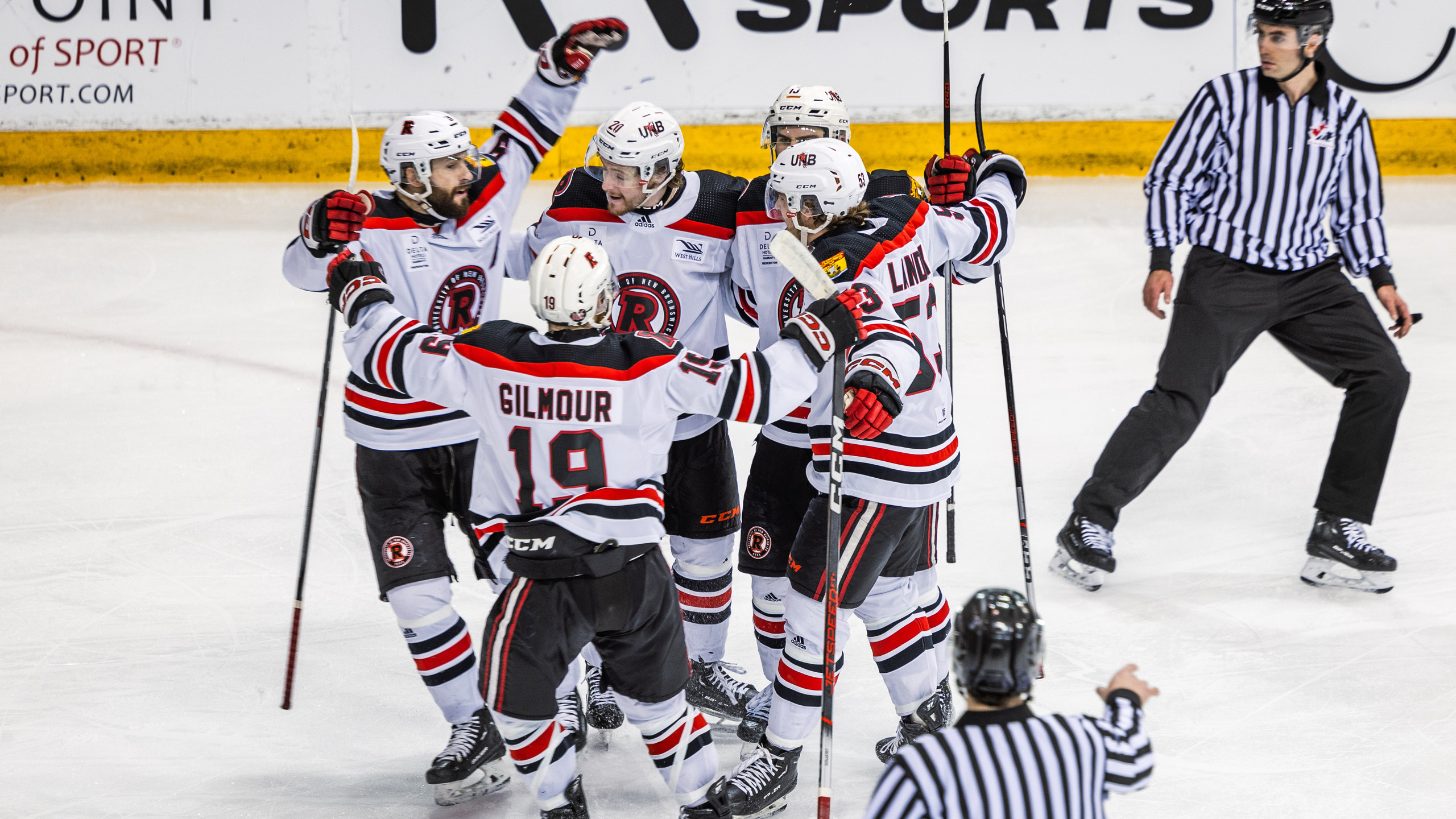 UNB players celebrate by hugging each other in a huddle