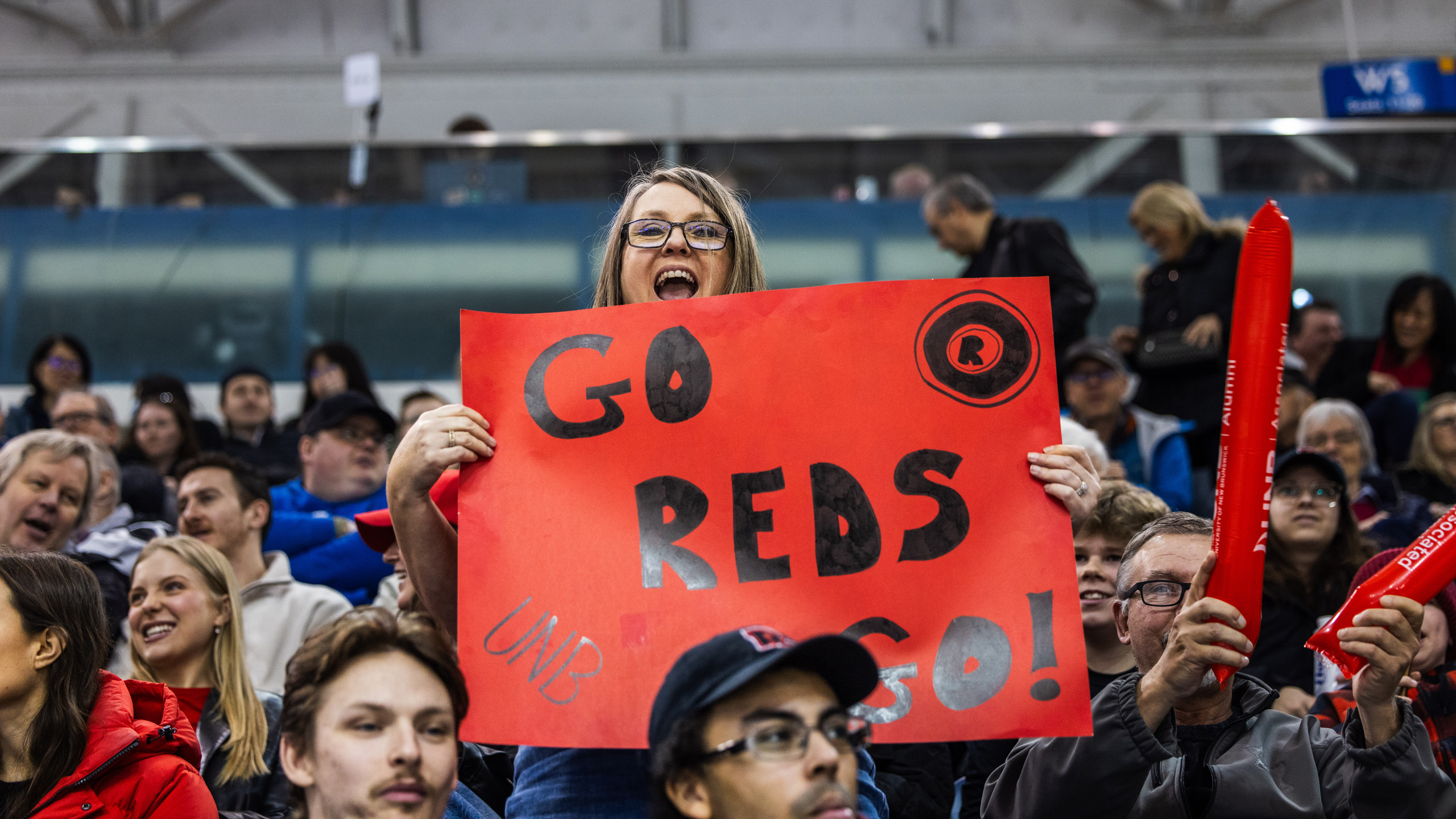 A UNB fan holds a sign that says "Go Reds Go"
