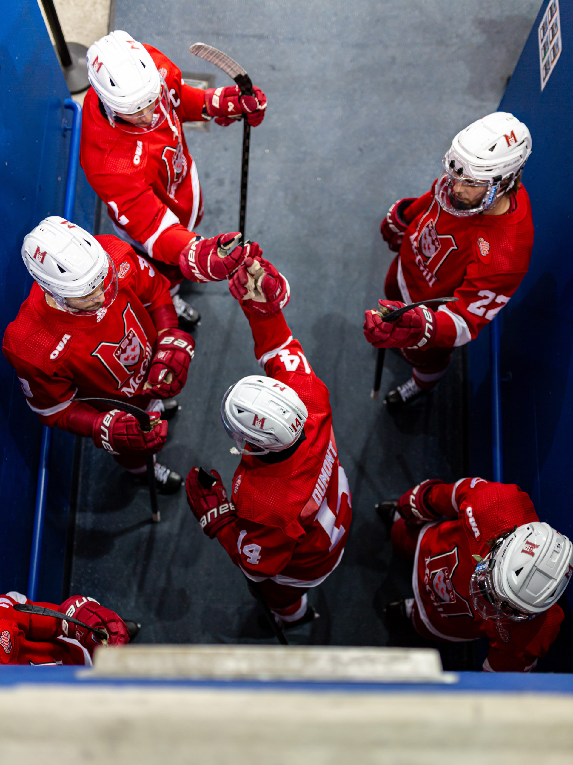 An overhead shot of five McGill Redbirds players fist bumping prior to the game