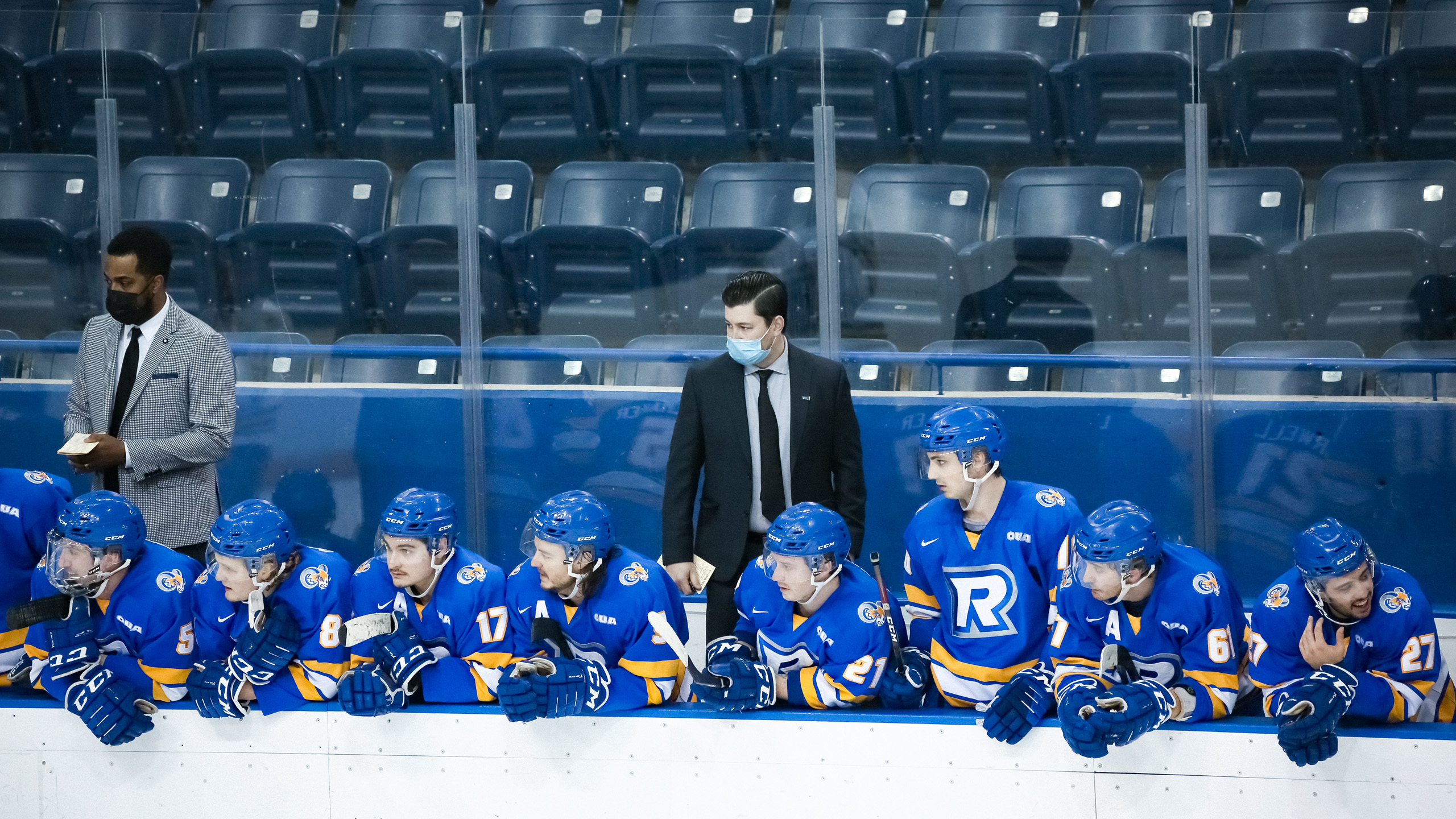 Former men's hockey coach Nathaniel Brooks stands to the left of head coach Johnny Duco behind the Ryerson Rams bench