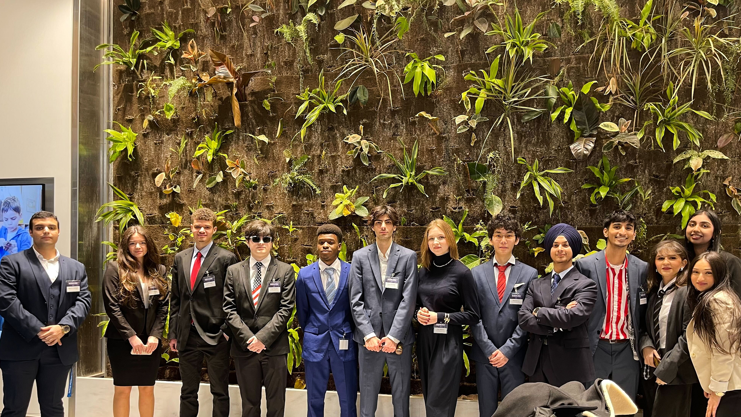 Group of people standing in front of a plant wall