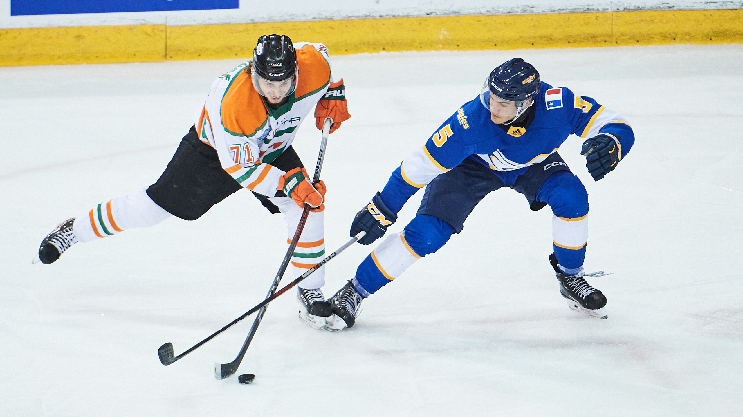 A UQTR player skates with the puck while a Moncton players tries to go for the puck