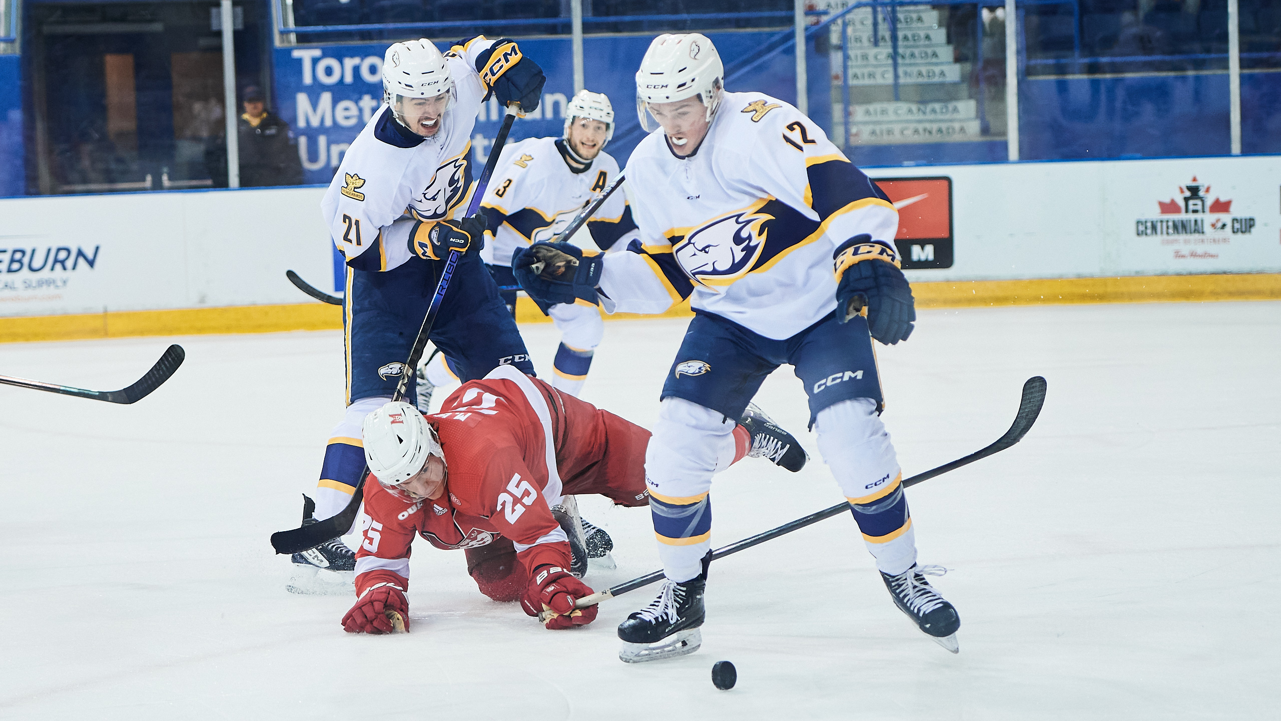 A UBC player fights for the puck over a McGill player
