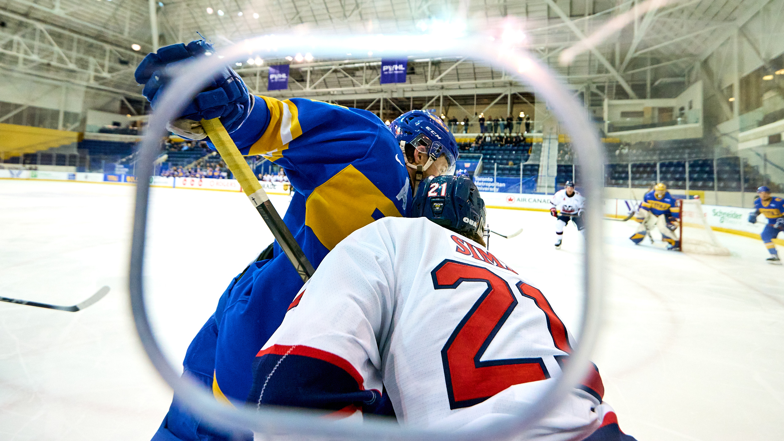 A TMU player and Brock player battle for a puck along the boards