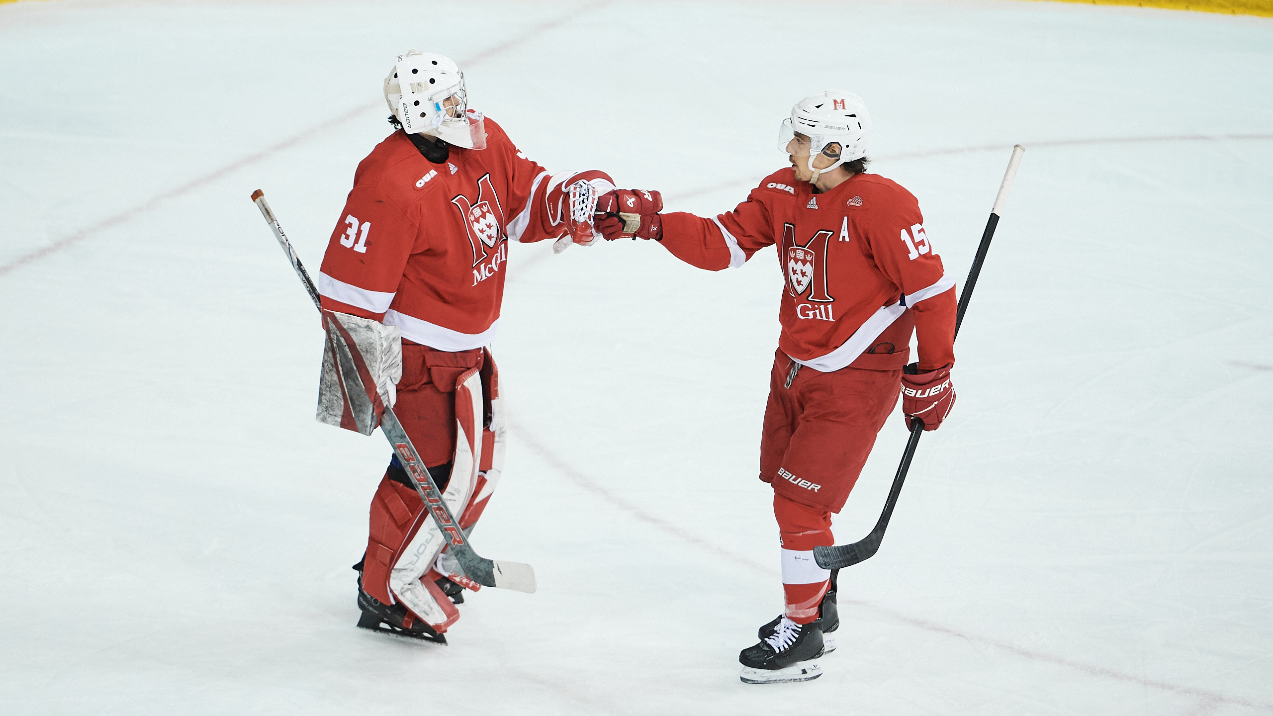 Two McGill University players fist bump on the ice