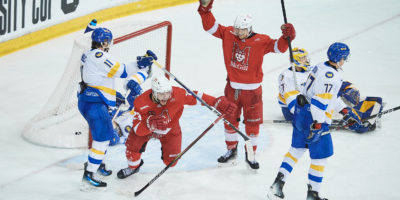 Two McGill Redbirds hockey players celebrate after scoring a goal on the TMU Bold net