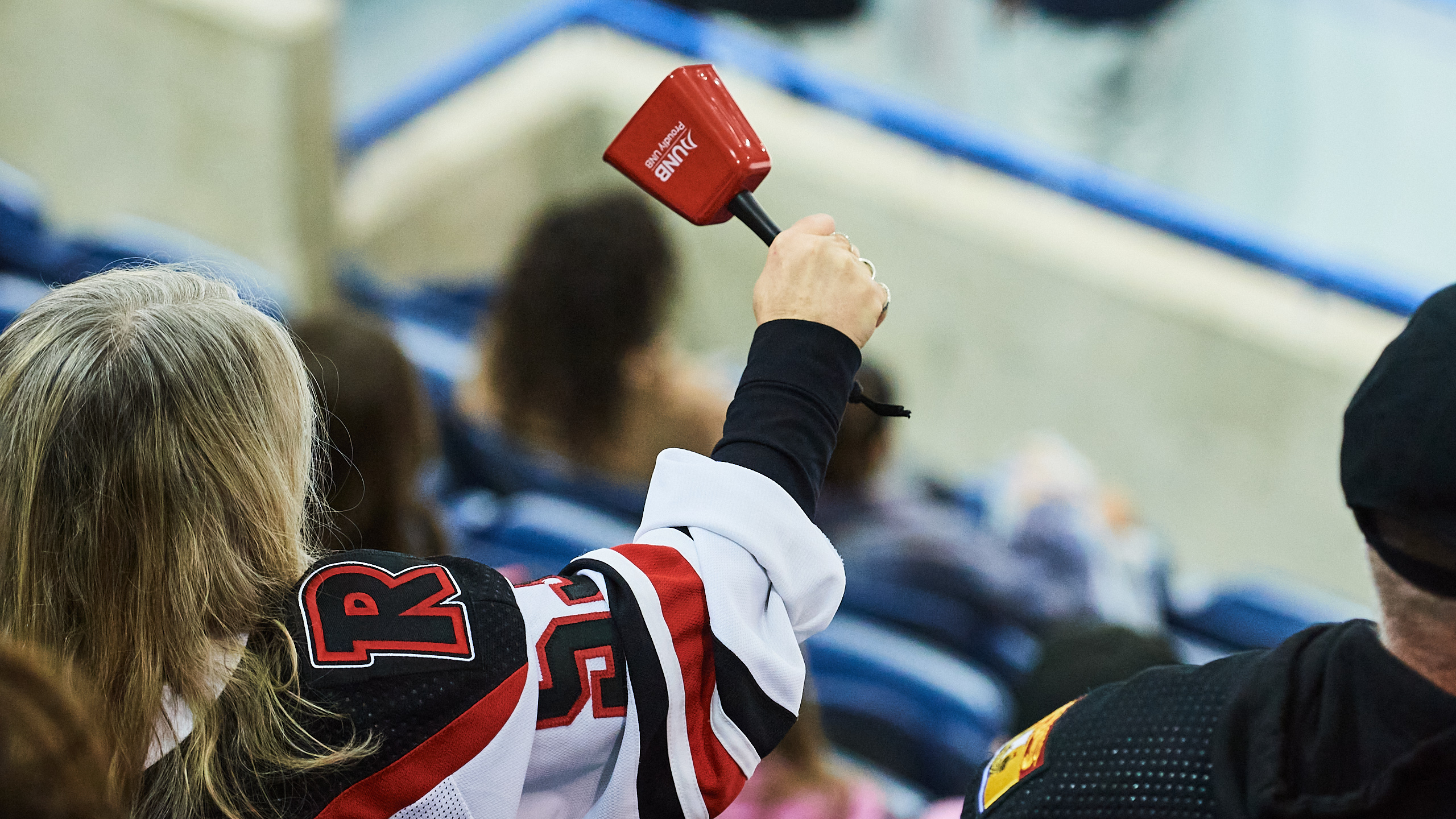 A UNB Reds fans waves a cowbell in the air