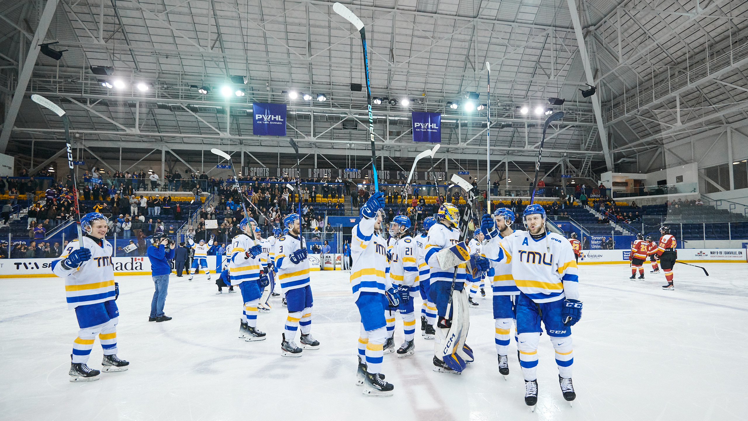 The hockey team hold their sticks in the air after a win