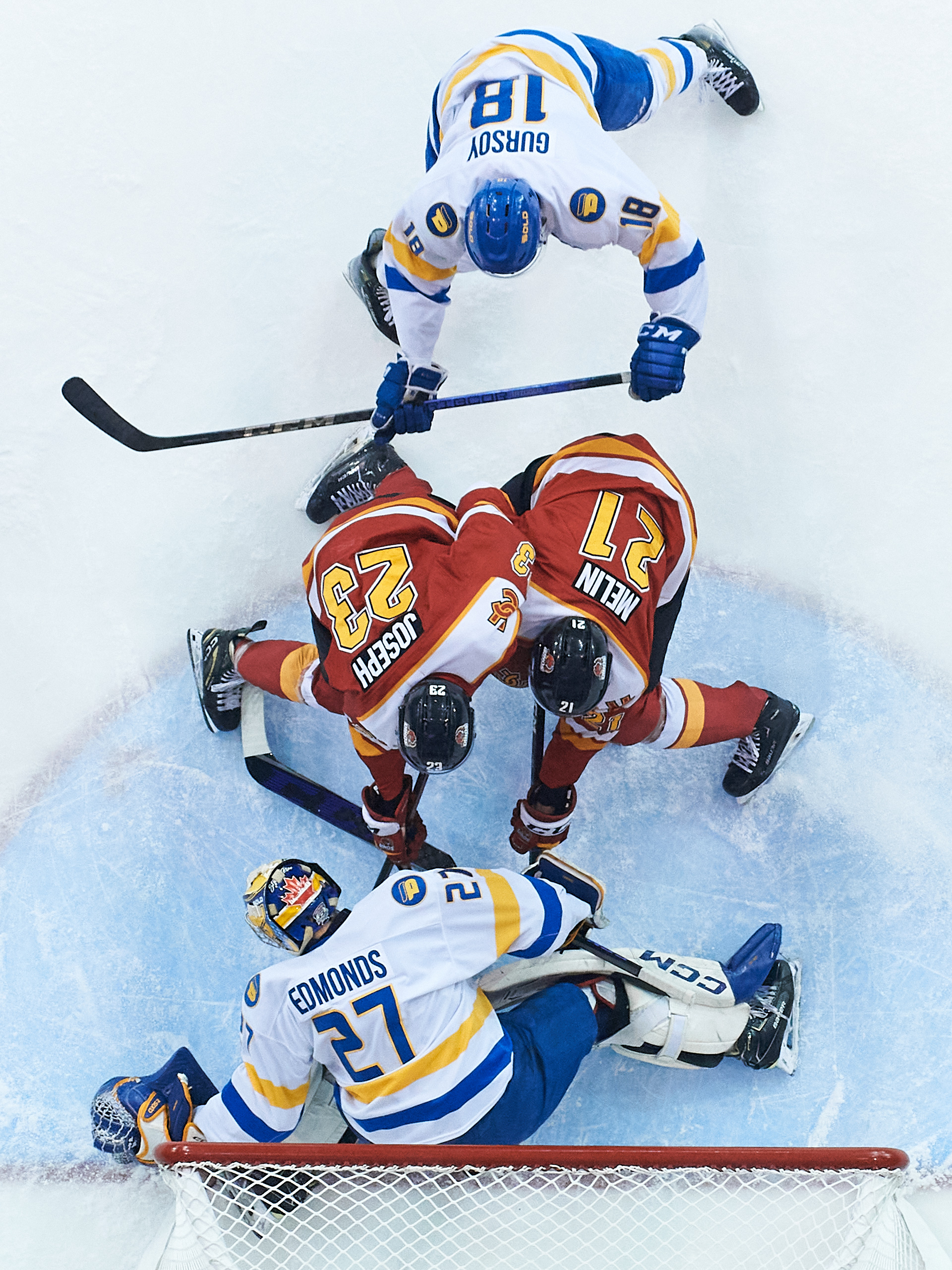 An overhead shot of a TMU player shoving two Calgary players into the TMU goal
