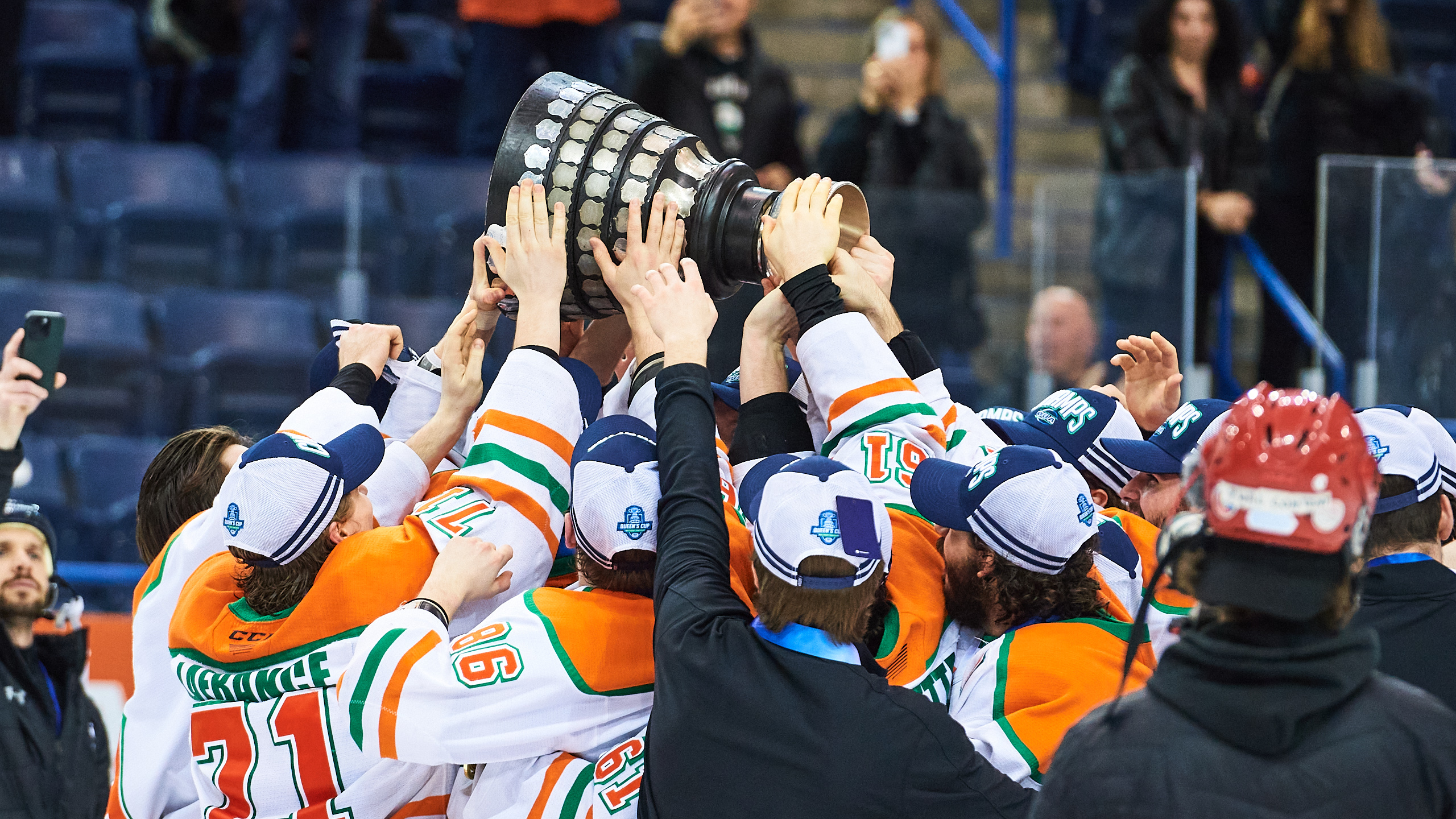 UQTR lifts the Queen's Cup as many players and staff touch the trophy
