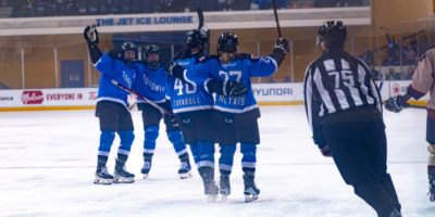 Two PWHL Toronto teammates hug each other as two other skate towards them in celebration of a goal