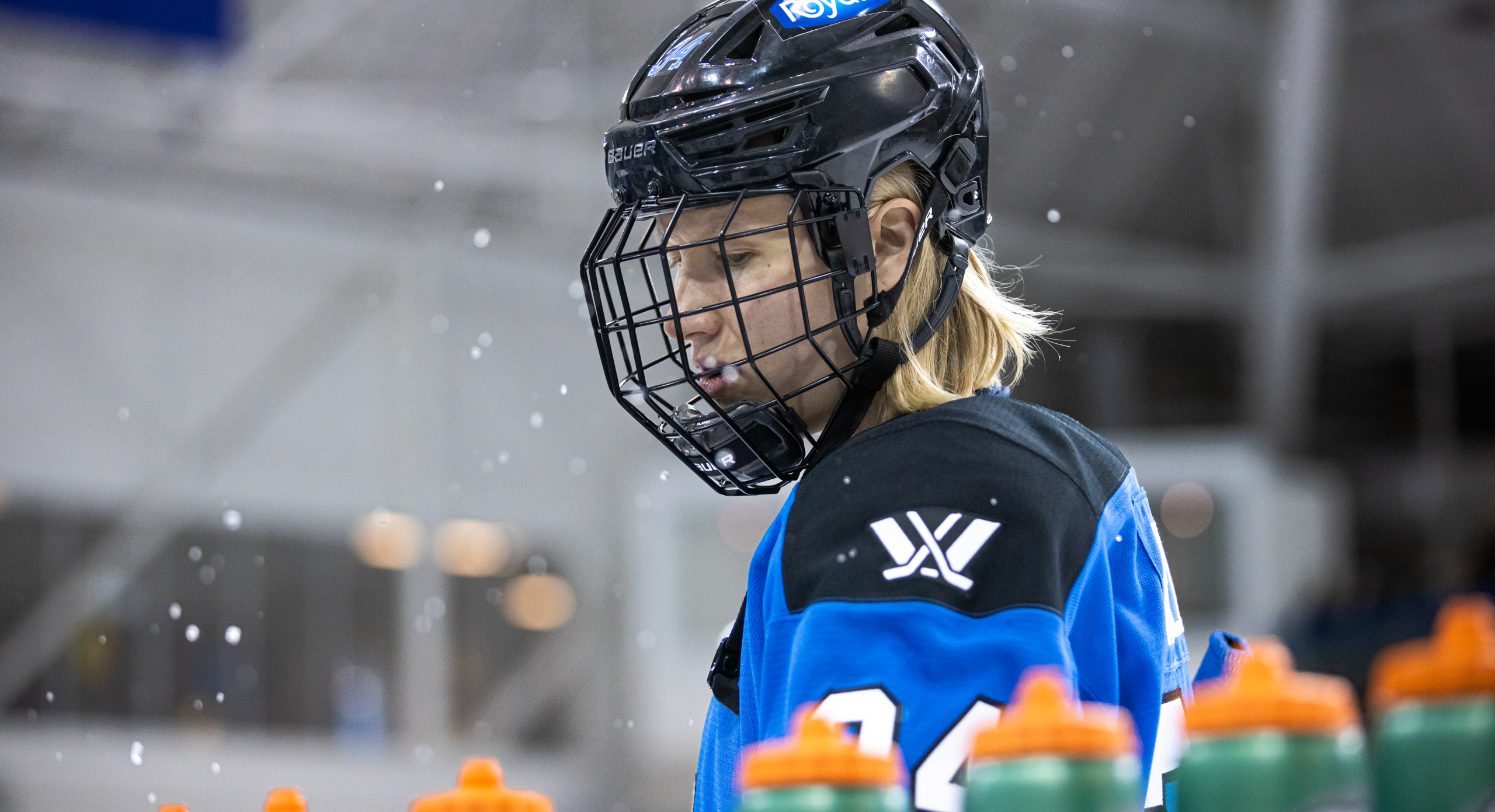 PWHL Toronto's Hannah Miller stares down at the bench with green water bottles on it. Water molecules are spraying up at her