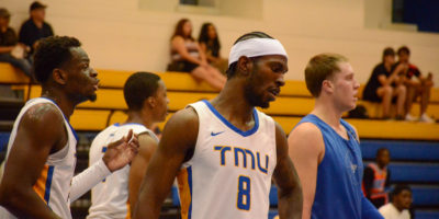 Thomasi Gilgeous-Alexander wearing a white TMU shirt with players in the background