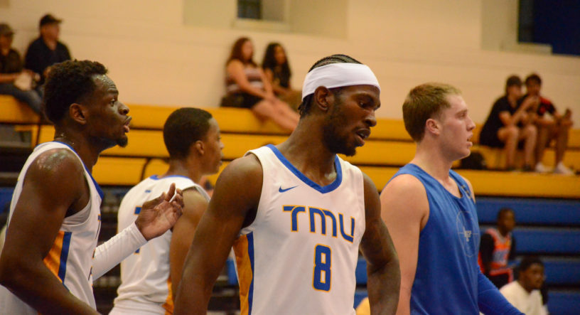 Thomasi Gilgeous-Alexander wearing a white TMU shirt with players in the background