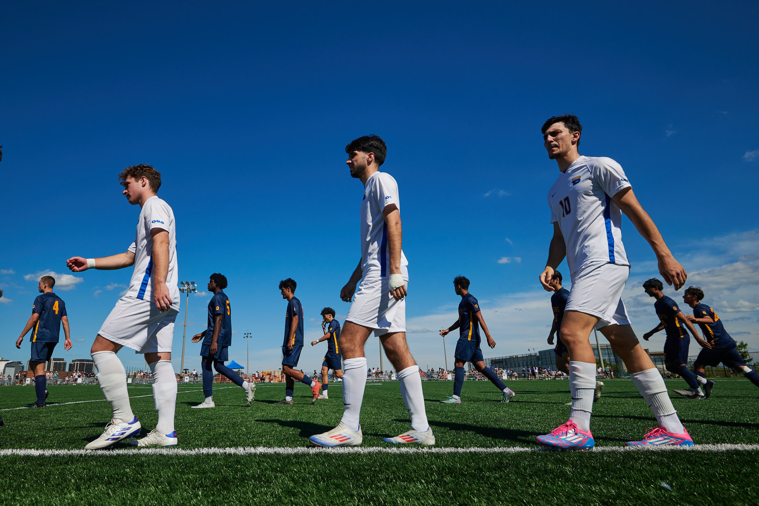 A photo from the ground up shows three TMU Bold players walking along the sideline after a win