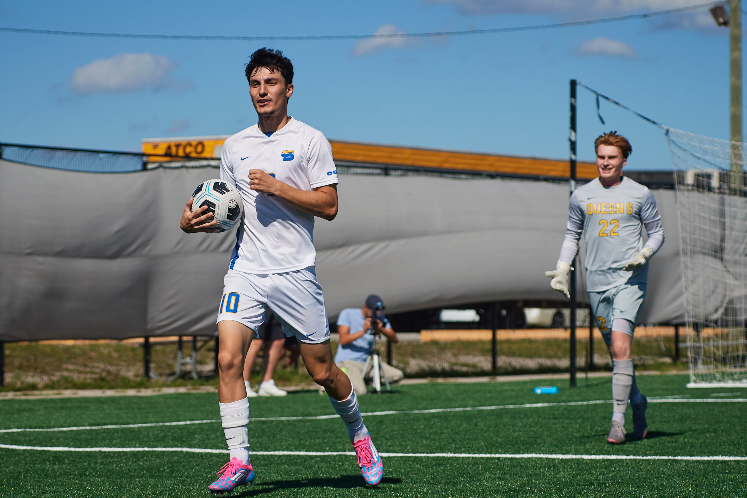 Chris Campoli struts with a soccer ball under his arm while the Queen's goalkeeper watches with his palms up