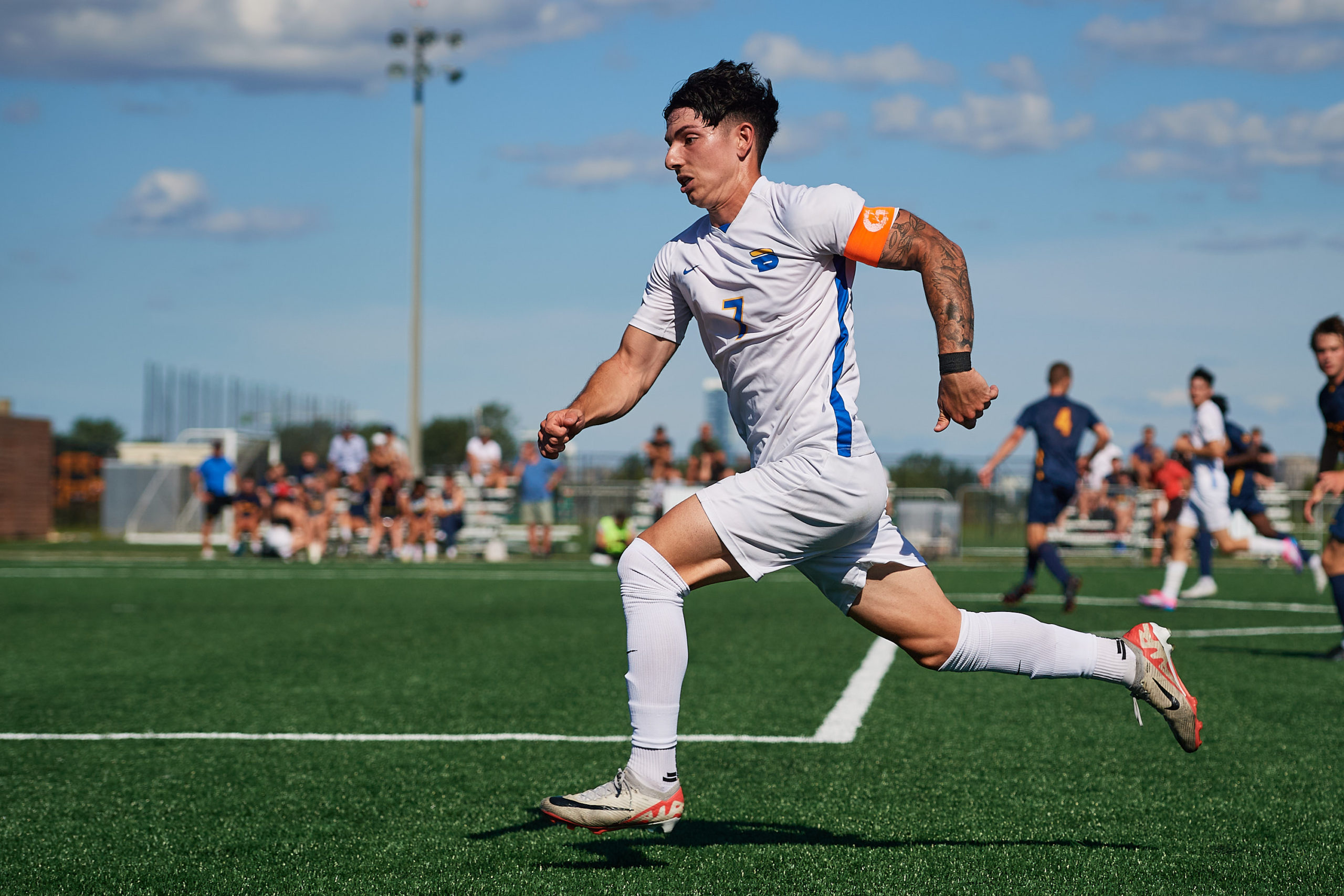 TMU Bold soccer player Luca Di Marco runs at full pace. He has an orange captain's armband