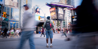 A student stands in the middle of a busy city centre