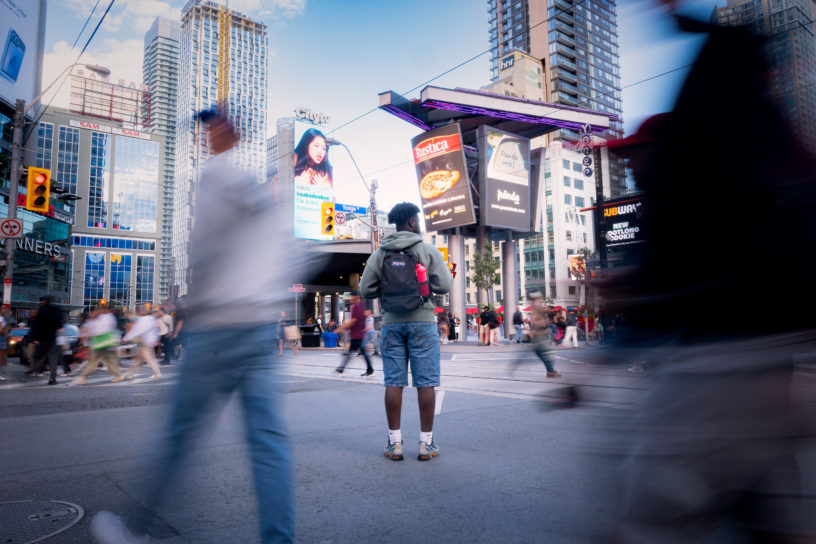 A student stands in the middle of a busy city centre