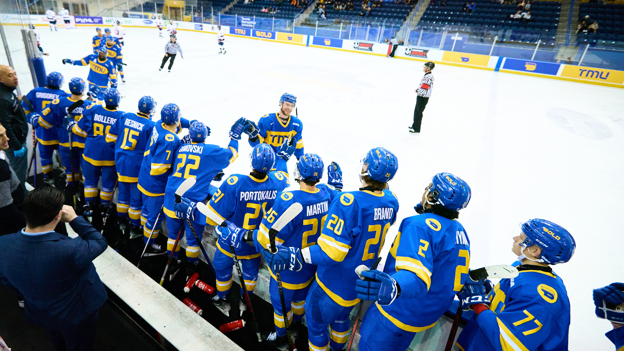 A male hockey team stands in line on the sidelines