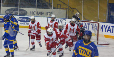 McGill Martlets women's hockey players skate towards their bench after a group hug to celebrate a goal. TMU players skate back to their bench