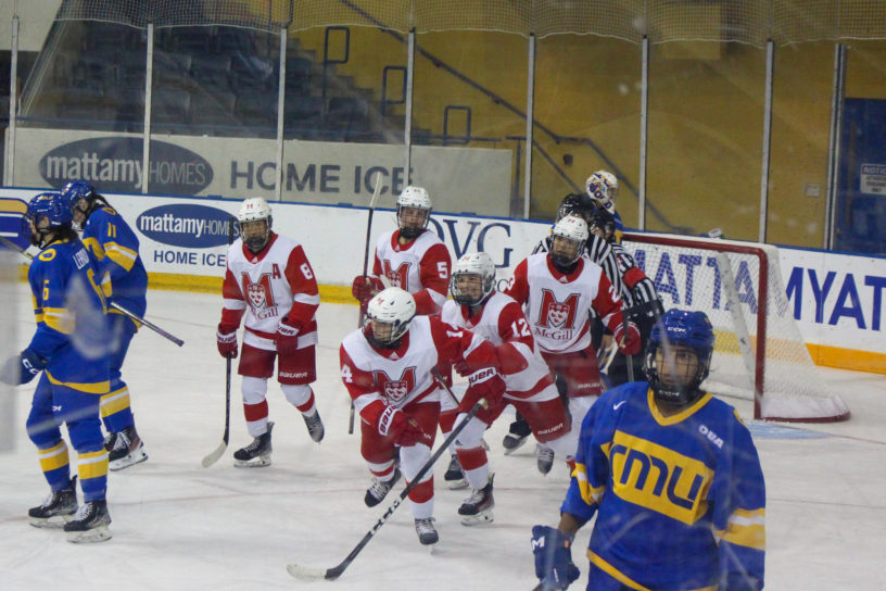 McGill Martlets women's hockey players skate towards their bench after a group hug to celebrate a goal. TMU players skate back to their bench